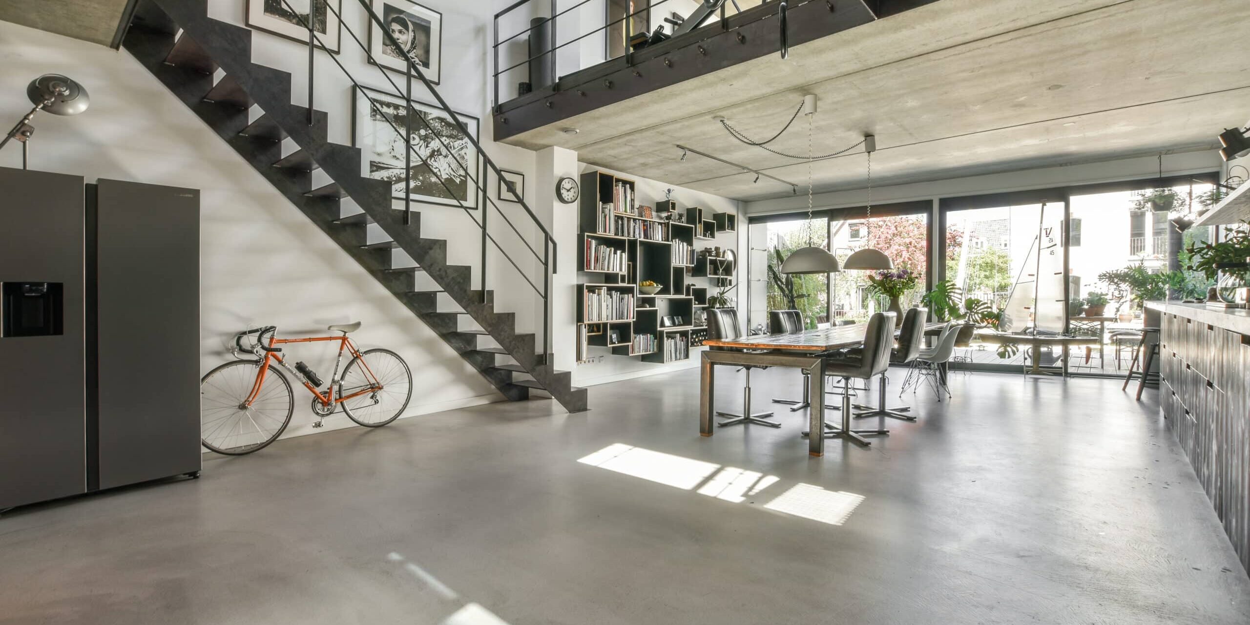 a living room with an open staircase leading up to the top floor, and a bike leaning on the wall